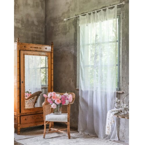 Tenda bianca trasparente con tessuto in misto lino, appesa a una finestra in un ambiente elegante e rustico.