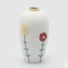 Vaso EDG in ceramica opaca bianca con motivi floreali in rilievo, altezza 27 cm e diametro 15 cm.