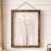 Quadro con cornice in legno scuro e fiori secchi incorniciati su sfondo trasparente.