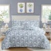 Set letto composto da una trapunta matrimoniale e due copriguanciali in tessuto floreale blu e bianco, ambientato in una camera shabby chic.