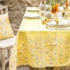 Tovaglia pasquale Blanc Mariclò 145x220 cm in poliestere, decorata con motivi di pulcini e fiori su fondo giallo, ideale per decorare la tavola.