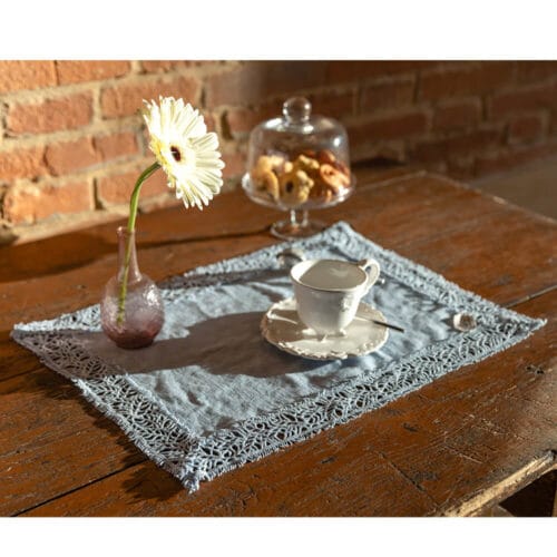 Tovaglietta all’americana color azzurro fiordaliso con bordo in pizzo Origami e tessuto in 100% cotone.