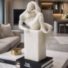 Statua decorativa in resina effetto marmo raffigurante un uomo in posa pensierosa su una base rettangolare, con dettagli anatomici finemente scolpiti.