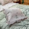 Cuscino quadrato in microfibra con stampa floreale su fondo rosa cipria e bordi arricciati, perfetto per uno stile romantico e shabby chic.