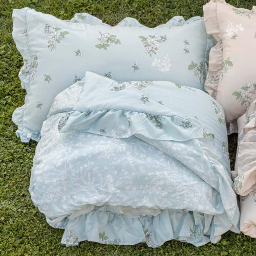 Trapuntino double face azzurro con fantasia floreale bianca e verde, completato da federe abbinate con bordo arricciato.