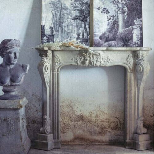 Cornice camino decorativa in stile barocco, con dettagli intagliati, finitura effetto pietra antica, struttura in legno, MDF e resina.