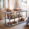 Consolle rettangolare in legno di pino con doppio ripiano, finitura grigia opaca e gambe tornite dallo stile country chic.