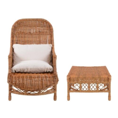 Poltrona in rattan con schienale alto e cuscini bianchi, accompagnata da uno sgabello coordinato con intreccio a vista.