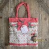 Borsa shopper in tessuto con fantasia natalizia: fiocco rosso, topina con regalo e logo Blanc Mariclò su sfondo decorato.