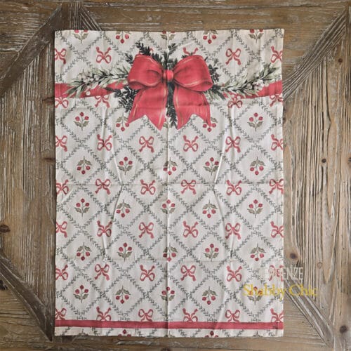 Canovaccio natalizio in cotone con stampa a fiocchi rossi e bacche, fiocco grande centrale e ghirlanda decorativa.