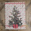 Canovaccio natalizio con stampa di albero di Natale addobbato e sfondo a rombi con fiocchi rossi e bacche.