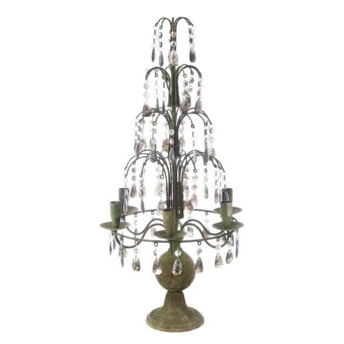 Candelabro vintage in metallo anticato con pendenti trasparenti e sei portacandele su struttura scenografica.