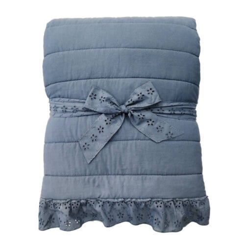Trapunta azzurra con cuciture orizzontali e bordo decorato con gala Sangallo, su letto singolo in stile romantico.