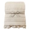 Trapunta beige con cuciture orizzontali e bordo in pizzo Sangallo, confezionata con fiocco decorativo e due copriguanciali abbinati.