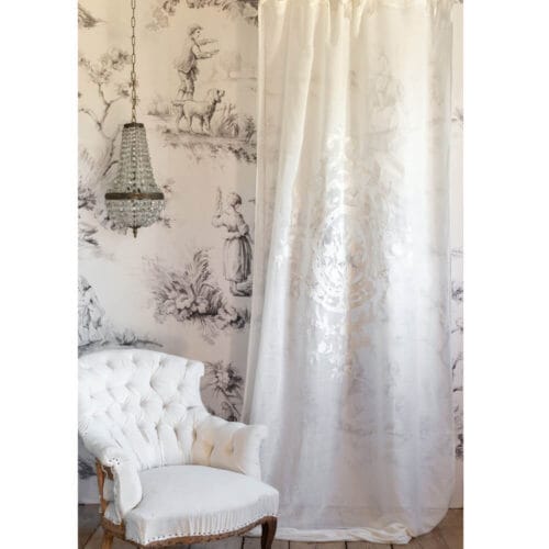 Tenda in lino e cotone bianco con ricamo medaglione centrale beige, appesa su fondo toile de Jouy.