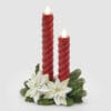 Centrotavola con due candele LED rosse a spirale, base decorata con fiori bianchi e foglie verdi in resina, confezionato in scatola bianca EDG.