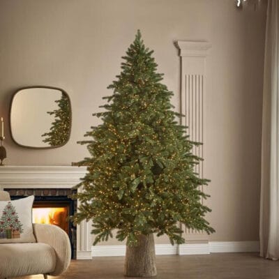 Albero di Natale EDG Pino Imperial New con 2500 luci calde e aghi effetto reale, ambientato in un salotto moderno con camino acceso.