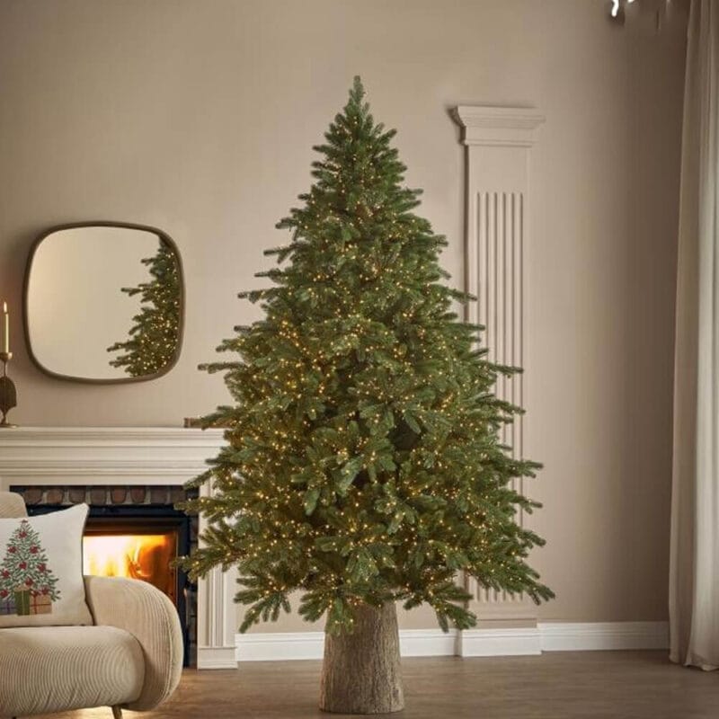 Albero di Natale EDG Pino Imperial New con 2500 luci calde e aghi effetto reale, ambientato in un salotto moderno con camino acceso.