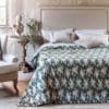 Trapunta matrimoniale verde con motivo floreale beige in rilievo effetto velluto, disposta su letto elegante in ambiente shabby chic.