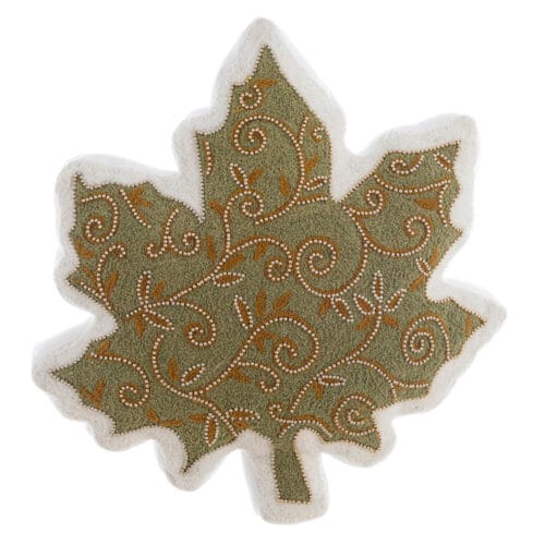 Cuscino decorativo a forma di foglia verde con ricamo a volute e perline dorate su tessuto bianco.