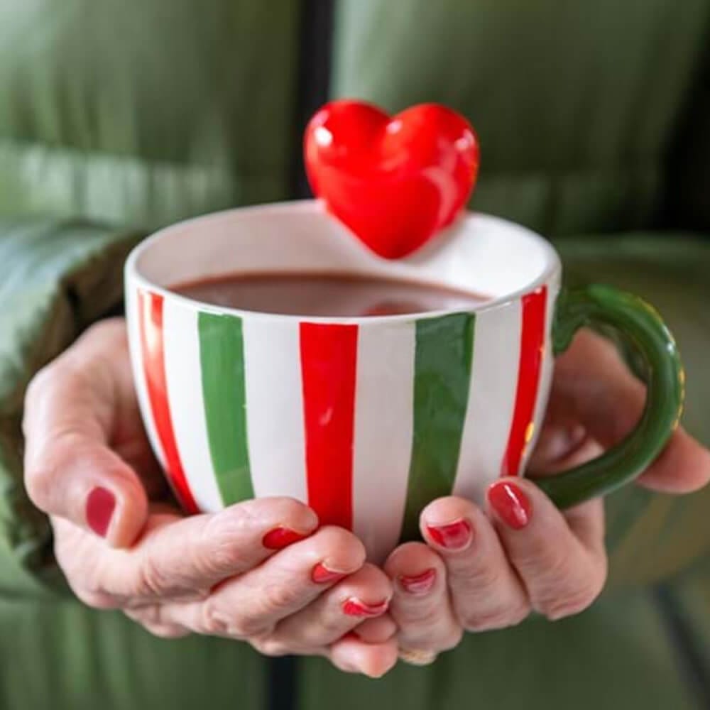 Tazza in ceramica con manico verde, righe verticali rosse e verdi e cuore rosso in rilievo sul bordo.