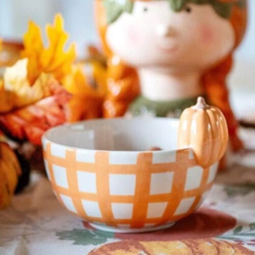 Ciotola bianca con motivo a quadri arancioni e decorazione a forma di zucca in rilievo.