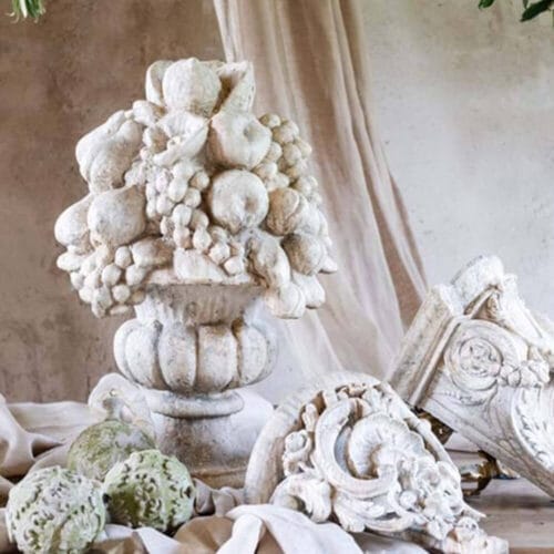 Statua decorativa Blanc Mariclò in resina anticata, raffigurante una composizione di frutta su base a calice, in stile classico.
