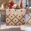 Runner natalizio in tessuto beige ricamato con motivo a losanghe verdi e croci rosse, bordo dorato intrecciato.