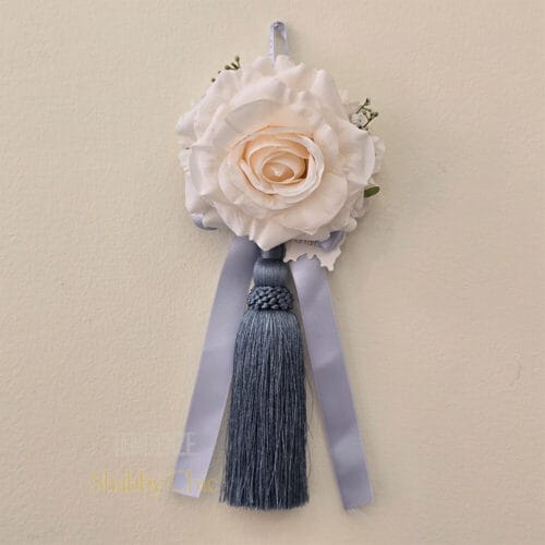 Nappa decorativa Fiori di Lena con rosa panna, ortensia e fiocco azzurro – ideale per maniglie, tende e ambienti shabby chic.