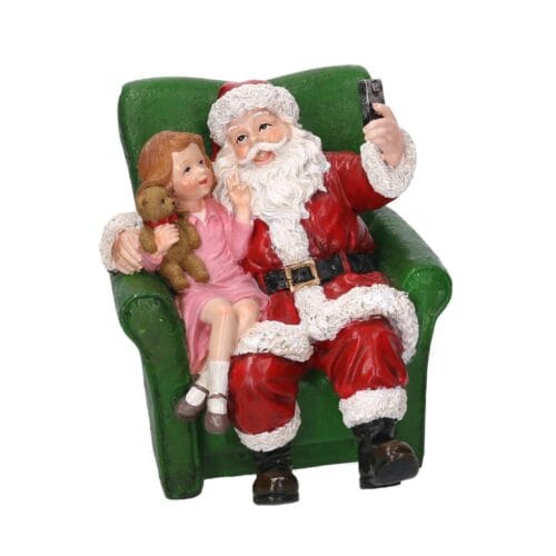 Statua Babbo Natale con bambina che scattano un selfie seduti su poltrona verde