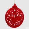 Medaglione decorativo natalizio in velluto rosso con disegno traforato a volute floreali.