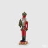 Statue de Noël en polyrésine représentant un soldat rouge avec un arbre décoré et une base avec des bordures dorées.