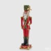 Statua natalizia in poliresina di un soldatino rosso con scettro dorato e decorazioni a tema foglie e pigne.