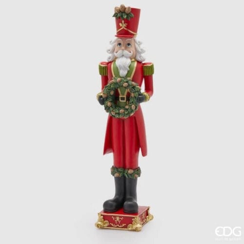 Statua di soldatino natalizio in poliresina, con ghirlanda verde decorata da pigne e dettagli oro.