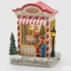 Carillon natalizio a forma di negozio di giocattoli con Babbo Natale, bambini davanti alla vetrina, albero, lanterna, neve e dettagli glitter.