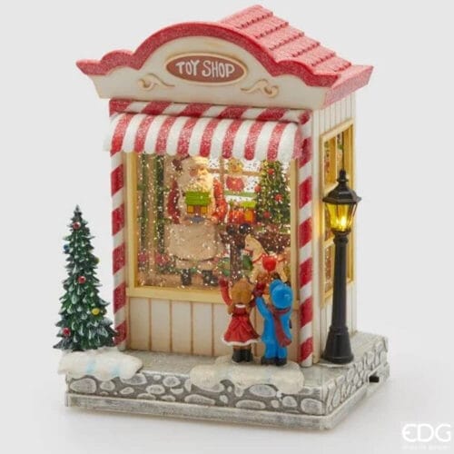 Carillon natalizio a forma di negozio di giocattoli con Babbo Natale, bambini davanti alla vetrina, albero, lanterna, neve e dettagli glitter.