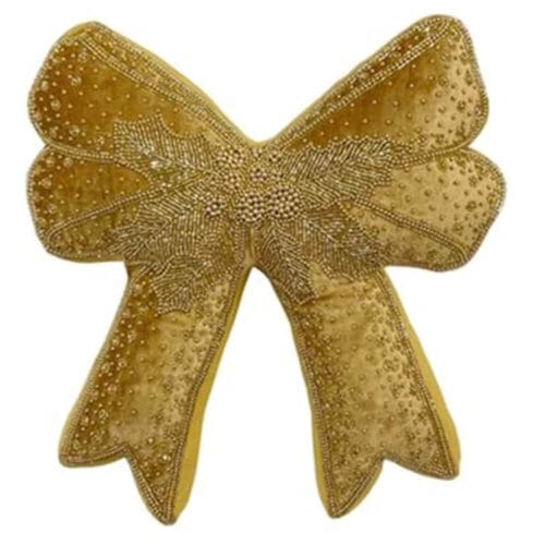 Cuscino decorativo dorato a forma di fiocco, impreziosito da ricami e perline, in un’atmosfera natalizia raffinata.