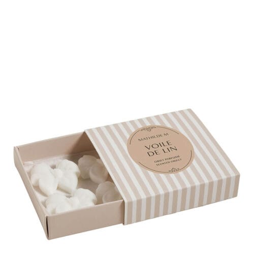 Cofanetto con quattro cere profumate bianche a forma di fiocco, disposte in una scatolina beige a righe firmata Mathilde M.