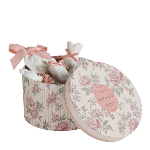 Cofanetto rotondo decorato con motivo floreale contenente 5 gessi profumati Mathilde M con fiocchi rosa, in forme assortite come bustina, cammeo, chiave e rosa.
