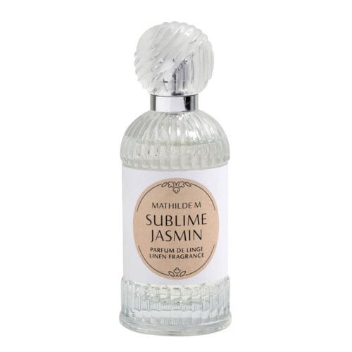 Flacone in vetro trasparente con tappo a rilievo e etichetta beige chiaro, contenente profumo per tessuti Mathilde M Sublime Jasmin.