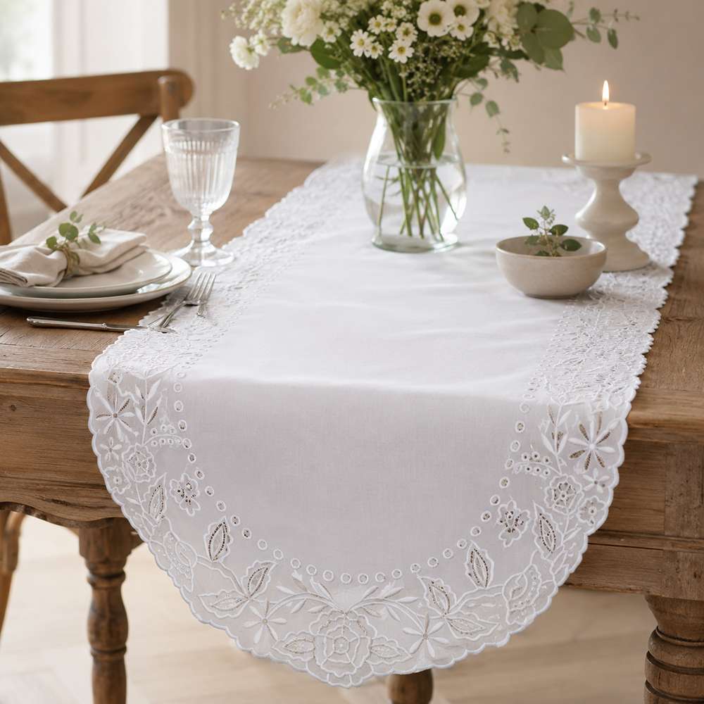 Runner bianco ricamato con motivi floreali e bordo sagomato della collezione Dentelle Blanc Mariclò.