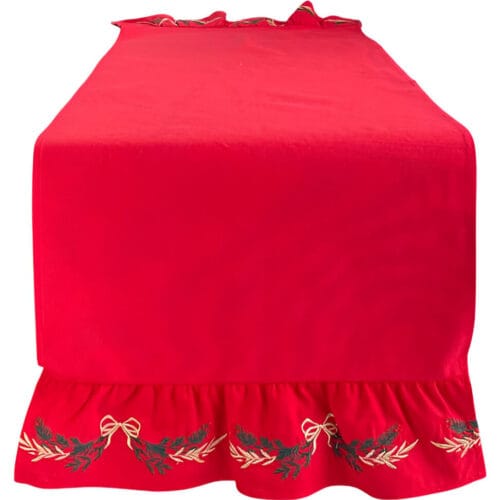 Runner in cotone rosso con balza ricamata, fiocchi dorati e decorazioni verdi in stile natalizio.