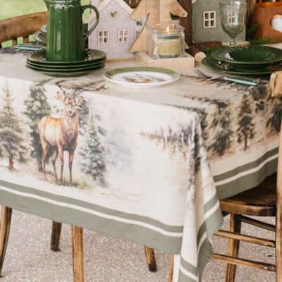 Tovaglia Nuvole di Stoffa in cotone 140x300 cm con decorazione natalizia di cervi e pini innevati, bordo verde salvia, perfetta per tavole grandi.
