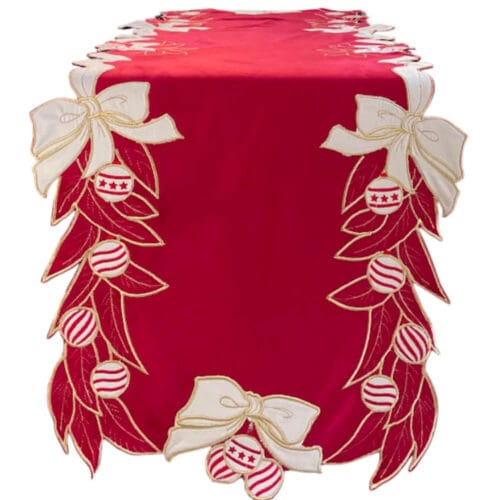 Runner natalizio in velluto rosso con ricami dorati, fiocchi bianchi e palline decorative sui bordi.