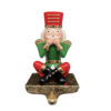Gancio decorativo natalizio a forma di schiaccianoci seduto con mani sulla bocca, base dorata per appendere calze o presine.