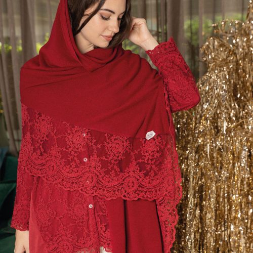 Stola invernale color mosto con balza in pizzo Corinzio tono su tono, indossata da una donna in ambiente elegante, con fondo dorato decorativo.