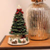 Albero di Natale decorativo con trenino rotante alla base, luci LED, decorazioni natalizie e case innevate, alimentato a batteria.