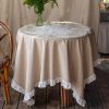 Copritavola beige 150x150 cm in cotone con applicazioni floreali bianche centrali e balza bianca plissé lungo il bordo.