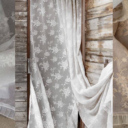 Tenda bianca in organza con ricamo floreale e bordo plissettato, appesa a una porta in legno rustico, in stile romantico e shabby chic.
