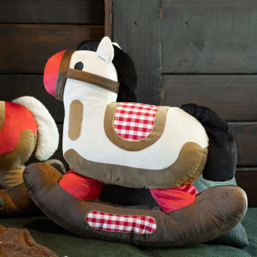 Cuscino decorativo a forma di cavallo a dondolo bianco, con criniera nera, dettagli rossi e fantasia a quadretti.